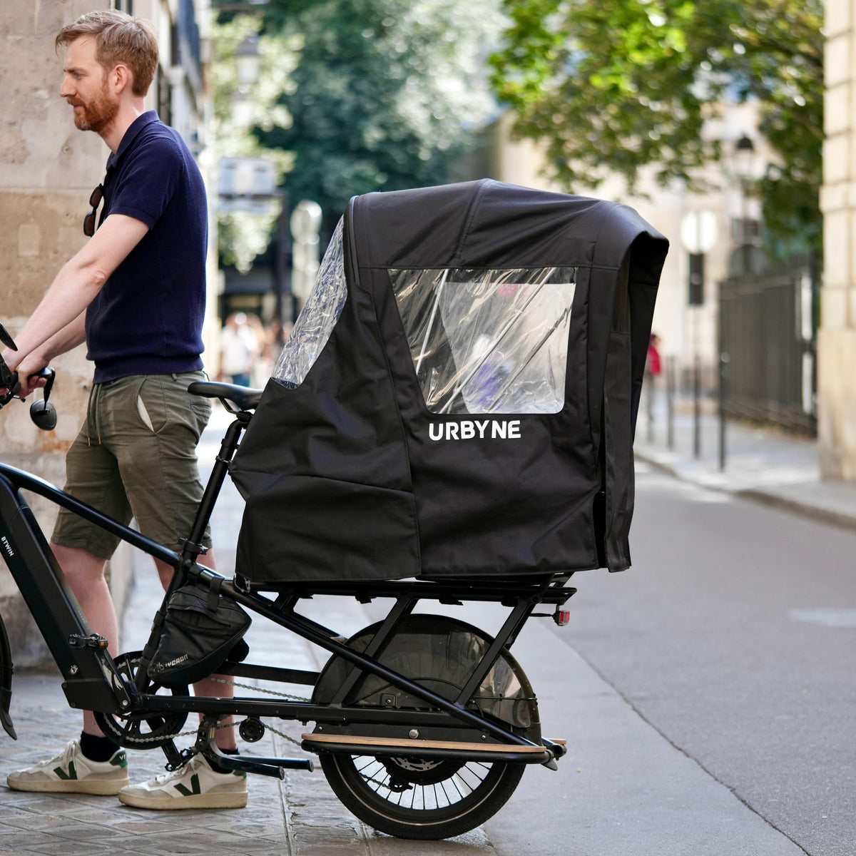 Housse de pluie Urbyne sur un vélo cargo longtail dans une rue de Paris